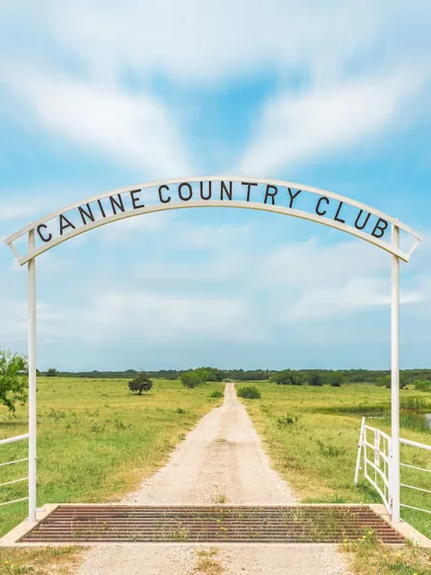 The Canine Country Club ranch gate on a gravel road